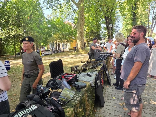 Obiskovalci med ogledom razstavljene policijske opreme na stojnicah, v okviru Dneva odprtih vrat Policijske akademije v Tacnu, Ljubljana, 6. avgusta 2026.
