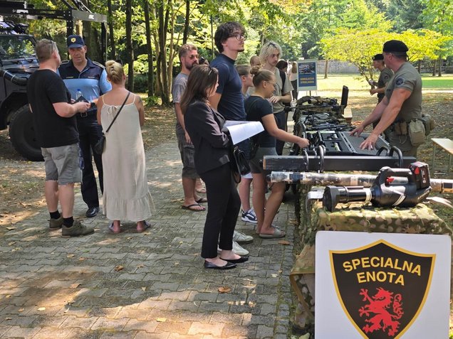Obiskovalci si ogledujejo opremo specialne enote policije, na stojnicah, v okviru Dneva odprtih vrat Policijske akademije v Tacnu, Ljubljana, 6. avgusta 2026.