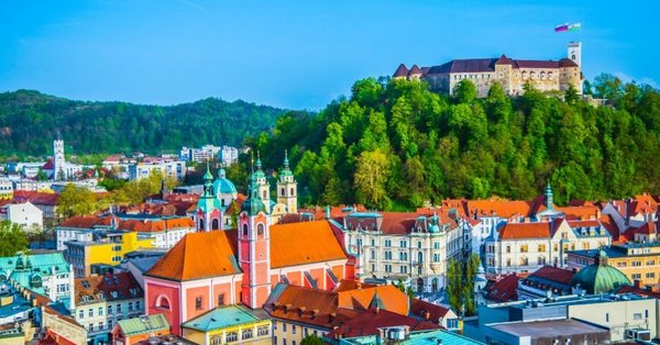 Panorama Ljubljane, obsijane s soncem, z Ljubljanskim gradom v ozadju. 