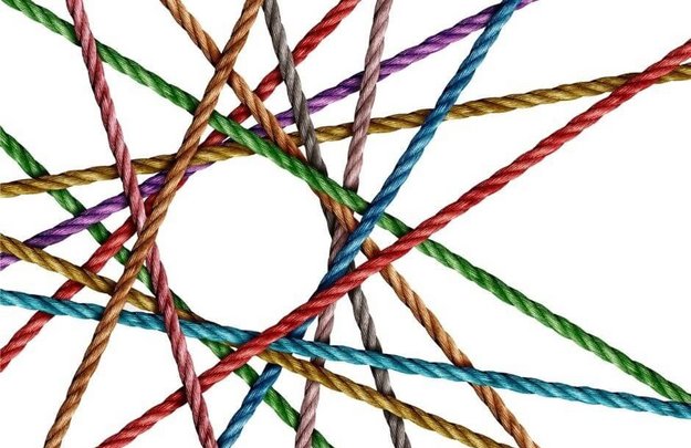 Simbolična slika. Raznobarvne vrvice (zelene, modre, rdeče, rumene, vijolične, sive) se križajo in prepletajo med seboj, tako da v sredini tvorijo obliko praznega kroga.
