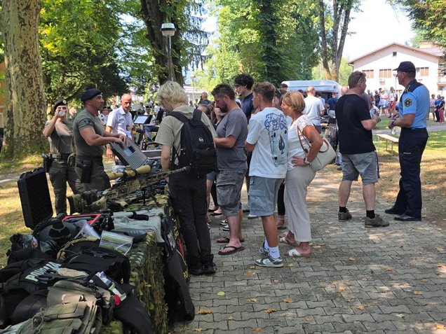 Obiskovalci si ogledujejo policijsko opremo na stojnicah, v okviru Dneva odprtih vrat Policijske akademije v Tacnu, Ljubljana, 6. avgusta 2026.